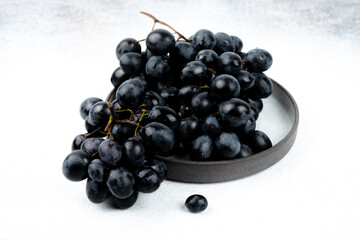 A bunch of black grapes on a white background. Fresh and juicy grapes.
