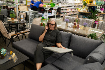 Senior woman shopping for outdoor furniture while on the phone in a home goods store