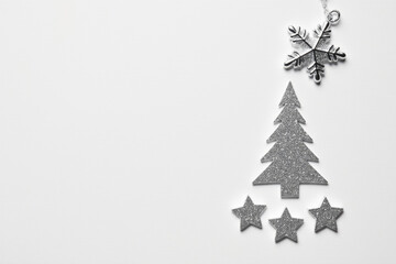 Minimalist festive winter background with sparkling silver Christmas tree, stars, and a snowflake arrangement, ideal for holiday season greetings and design projects