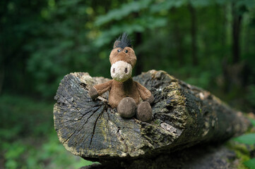 Close-up of a soft brown plush horse toy sitting against a beautiful blurred background, creating a warm and gentle composition.