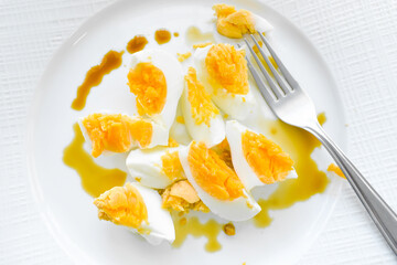 Boiled egg with soy sauce with a fork on a white plate. Healthy and dietary food.