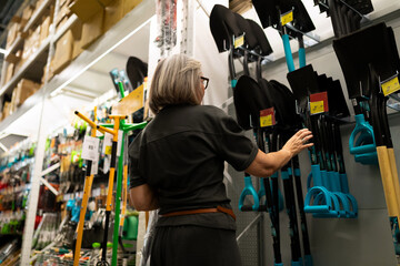 Choosing gardening tools in a store aisle with a focus on shovels and spades