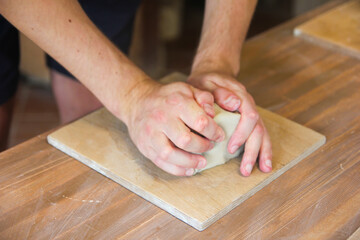 Hands Kneading Clay on Wooden Table in Pottery Workshop