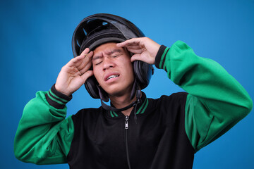 Stressed Indonesian Ojol Driver in Uniform Clutching His Temples Suffering From Severe Headache or...