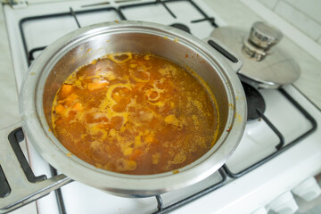 Boiling pumpkin soup in stainless steel pot on gas stove