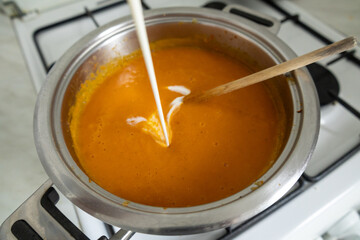 Adding cream to homemade pumpkin soup