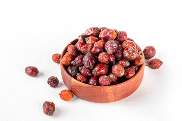 Bowl of dried rose hip berries on white background, healthy ingredient for cooking drinks, tea, healthy cocktails