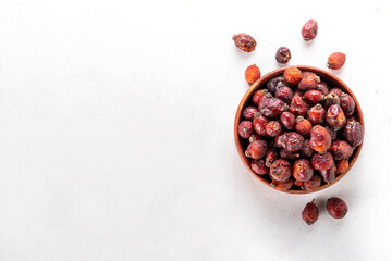 Bowl of dried rose hip berries on white background, healthy ingredient for cooking drinks, tea, healthy cocktails