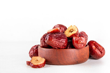 Bowl of dried red unabi or jujube berry fruits, healthy asian fruit, Chinese dates halfed and whole on white background