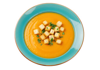 Isolated butternut squash soup in a blue bowl with croutons and parsley as garnish