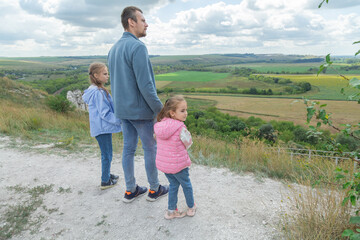 Father and daughter stand on scenic landscape