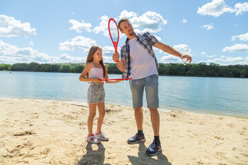 Father teaching beach tennis to daughter while standing on sand on beach