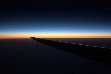 Airplane wing at dawn aerial view from flight window perspective over cloudscape and horizon