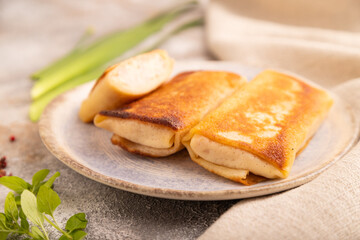 Fried crispy pancakes with meat and cheese on brown concrete and linen textile. side view, close up, selective focus