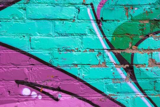Vibrant graffiti art on brick wall in purple and teal with geometric shapes. 90s style, vibrant colors, street art vibe. Urban designs, posters, digital backgrounds, creative banners.