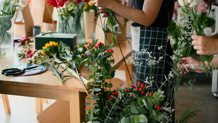 Focus on Hypericum branches and fresh flowers arranged during a creative floral workshop