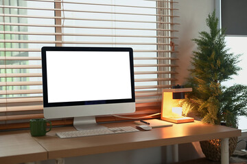Minimalist workspace with computer, desk lamp, and coffee mug by window in warm light.