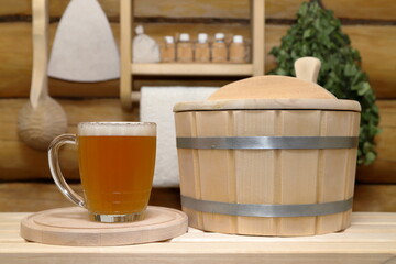 In the sauna interior on a bench against log wall with birch broom, ladle, hat and shelf with set...