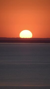 big sun quickly sets behind the horizon, seascape, orange light.