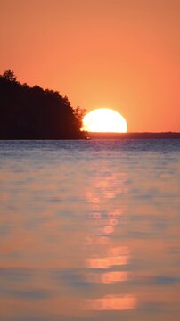 Fast river water, sunset, orange light, island and sun on the horizon.