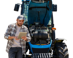 Fototapeta premium Agricultural machinery mechanic using a computer tablet near the tractor.
