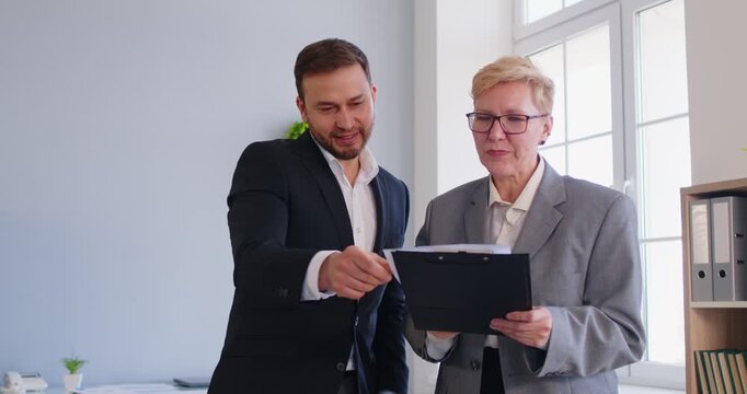 Adult mature business woman and young confident business man meet, introducing at business chat to partners, businesspeople making agreement, greeting each other, friendly shaking hands, explain