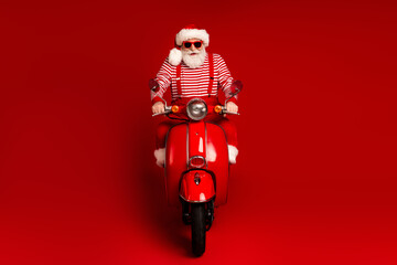 Santa on a red scooter rides against a bold red background in a festive Christmas themed image