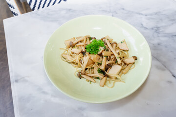 A delightful pasta dish with mushrooms arranged on a light-green plate, showcasing culinary artistry. The dish is an appetizing image 