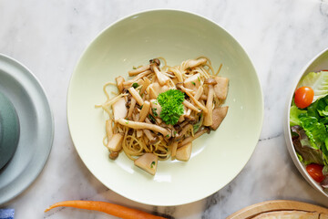 A culinary delight: a plate of delicious pasta with mushrooms, accompanied by a fresh salad.
