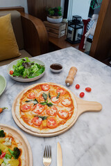 Delicious pizza on wooden board, salad, tomatoes on a marble table