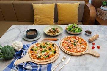 Delicious, colorful vegetarian pizzas and side dishes are served on a marble table, creating a...