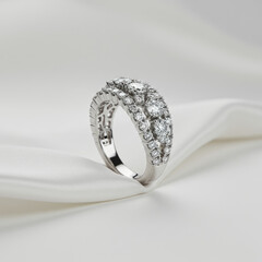 Close up of a platinum diamond ring with multiple rows on a white silky background