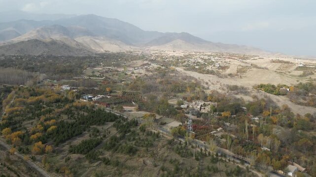 Aerial drone view of mountain villages and forest with golden autumn colors over Paghman region near Kabul, Afghanistan