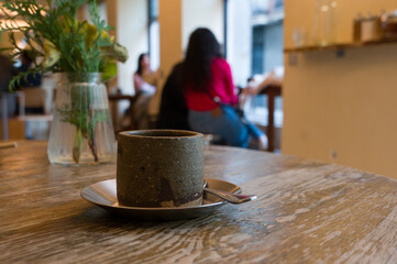 Coffee cup on wooden table in cafe, atmosphere of a coffee shop in bokeh background