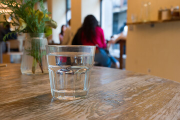 Glass of water and carafe on wooden table in cafe, atmosphere of a coffee shop in bokeh background