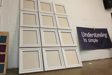 White empty photo frames arranged in a grid leaning against a wall