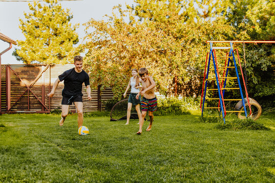 Teens and kids playing football together in a sunny back yard