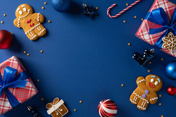 Colorful Christmas scene with gingerbread cookie, present, ornament, candy cane, ribbon and festive decor on a deep blue background, perfect for holiday greeting cards and New Year celebrations