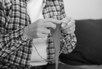 Black and white photo of knitting process. Woman focused on handmade craft, symbolizing calmness and mindfulness.