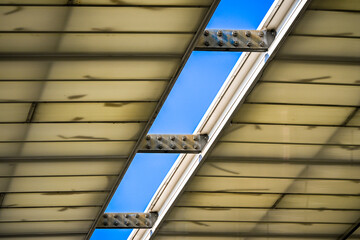 Obraz premium Detail view of a translucent roof made of corrugated panels and metal beams, allowing natural light to filter through the structure.