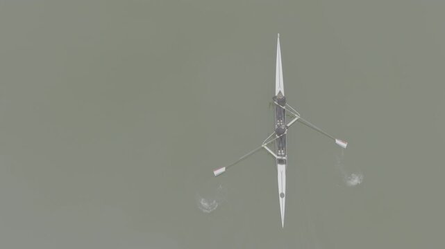 Two athletes rowing a sculling boat on calm water, teamwork and endurance in competitive sport. Practicing sport rowing. Rowers in a racing boat row in slow motion video. ProRes 422 10 bit DJI D-Log.