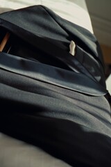 a black suit that is laid on the edge of a bed with white bed sheets