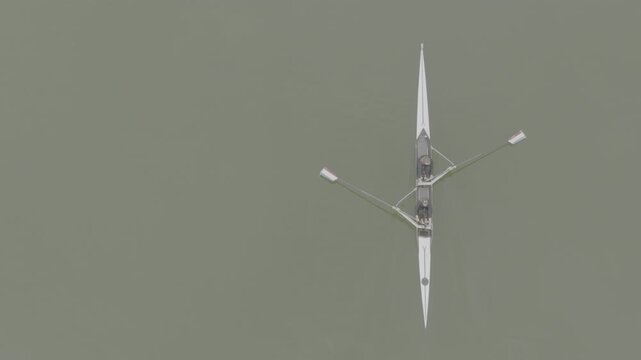 Two athletes rowing a sculling boat on calm water, teamwork and endurance in competitive sport. Practicing sport rowing. Rowers in a racing boat row in slow motion video. ProRes 422 10 bit DJI D-Log.