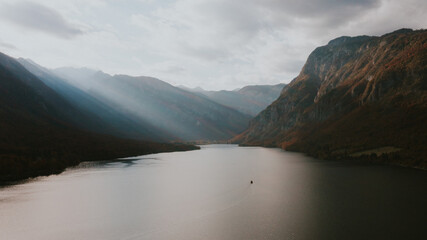 Moody light over mountain valley and lake Bohinj in Slovenia. Aerial landscape view of a mountain valley and winding lake under dramatic light. Sunrays break through the clouds.