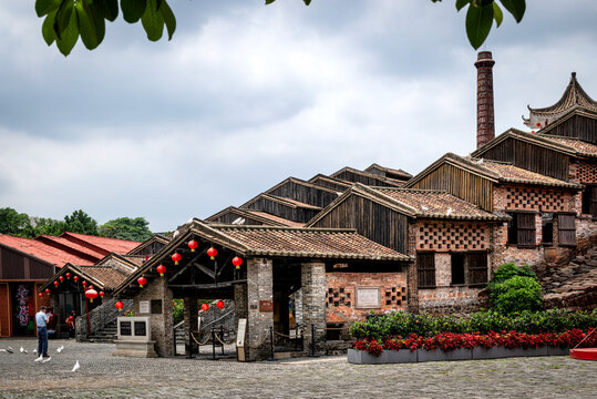 Visitor admiring Foshan's Nanfeng Ancient Kiln traditional building on a cloudy day