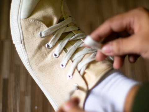 Close up hands tying white canvas sneakers shoelaces getting ready to go out or exercise
