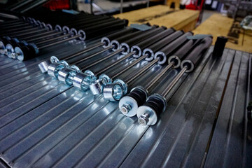 Obraz premium A close-up view of several shiny metal industrial components, possibly nuts or sleeves, lined up on a grooved metal shelf in a factory or warehouse.