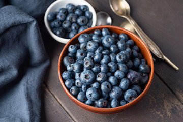 Blueberries in bowl on a wooden table. Healthy summer berries