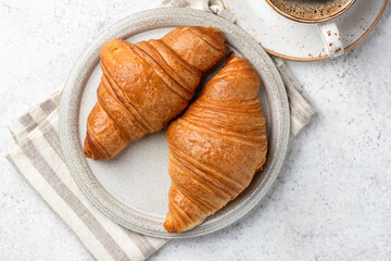 Closeup view two french flaky croissants served on a plate with cup of coffee. Delicious breakfast or coffee break meal