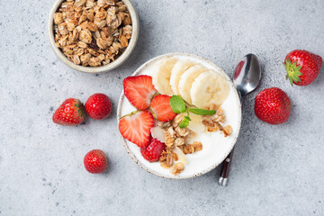 Yogurt bowl with muesli, banana and strawberries. Healthy diet fitness meal for weight loss and wellbeing